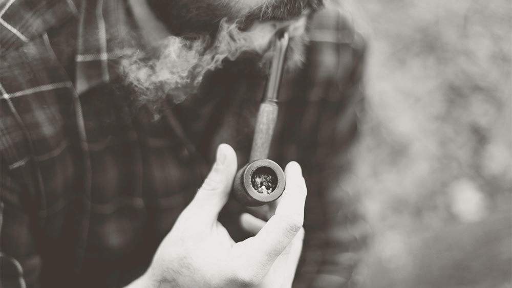 poza alb negru cu barbat care fumeaza din pipa